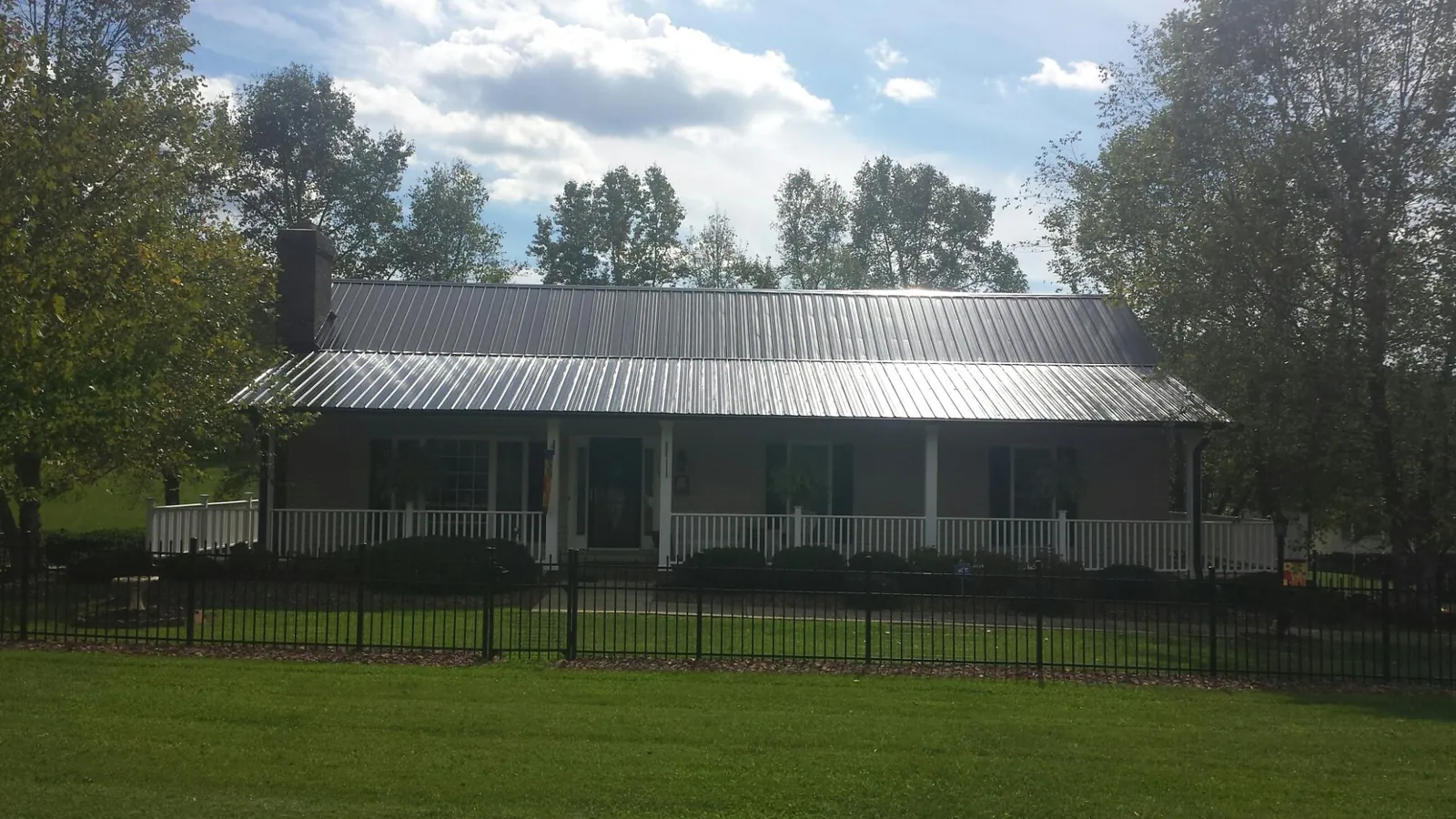 Gray metal roof on a brick ranch with a full width front porch — Gutter Guard Installation work by our crew in Anderson